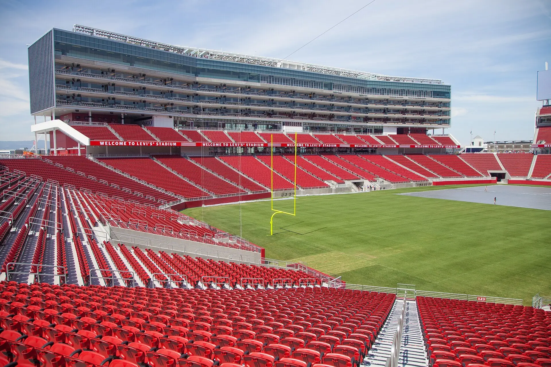 Levi's Stadium seating bowl and grass field in bright sun, looking across the end zone toward the suite tower and scoreboard
