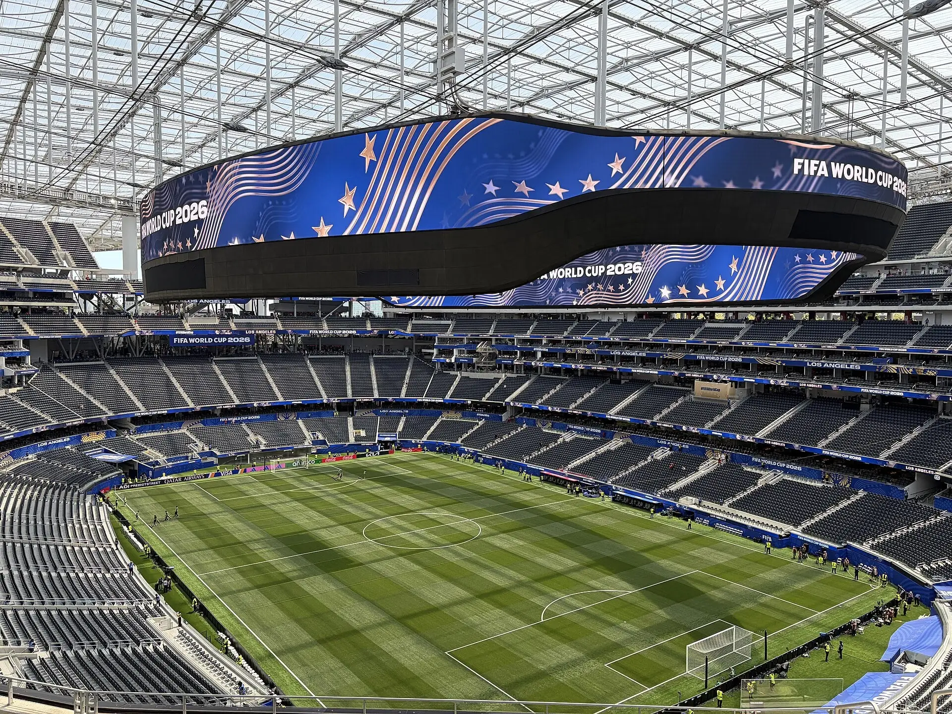 Wide view of the SoFi Stadium seating bowl and translucent canopy from the upper deck, set up for a soccer match with the oval video board overhead
