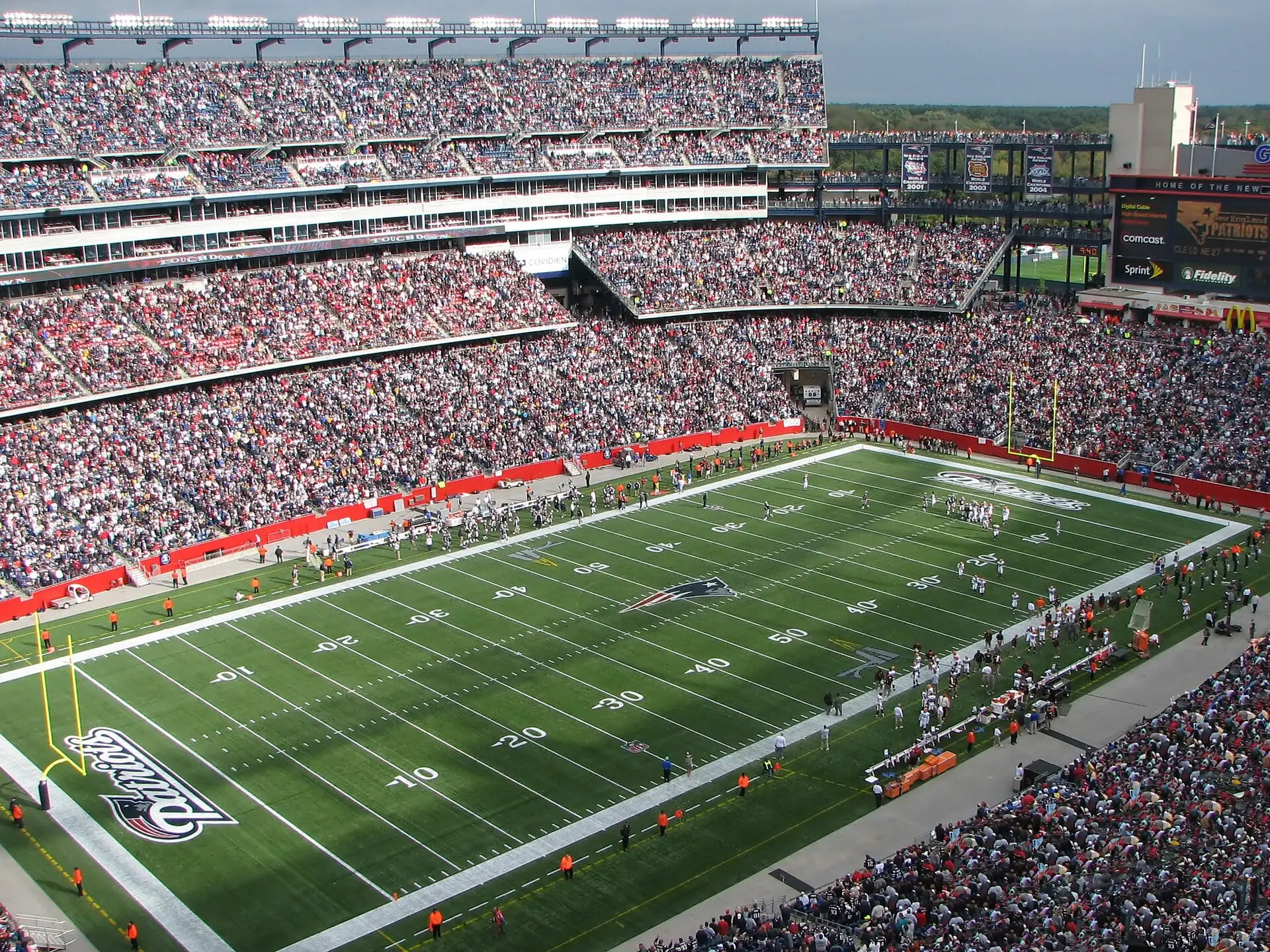 Gillette Stadium on a sunny game day, looking across the field from the upper deck toward the far stands and scoreboard tower