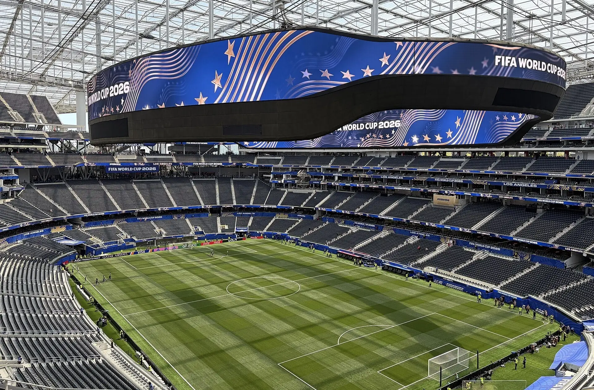 Wide view of the SoFi Stadium seating bowl and translucent canopy from the upper deck, set up for a soccer match with the oval video board overhead